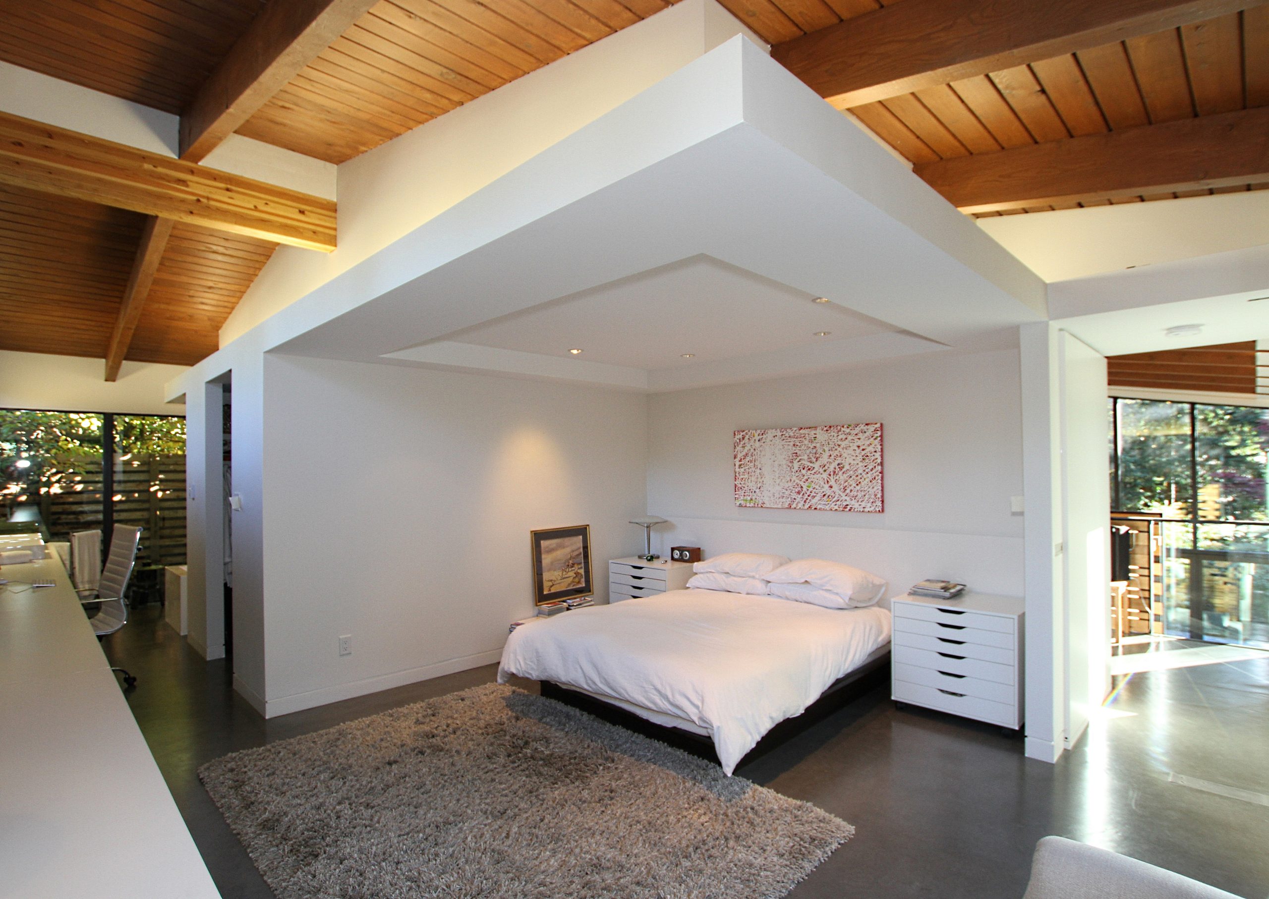 Open concept bedroom with wooden ceiling, white walls, and large windows showcasing quality architecture and natural light—a perfect retreat designed by a reputable company in Vancouver