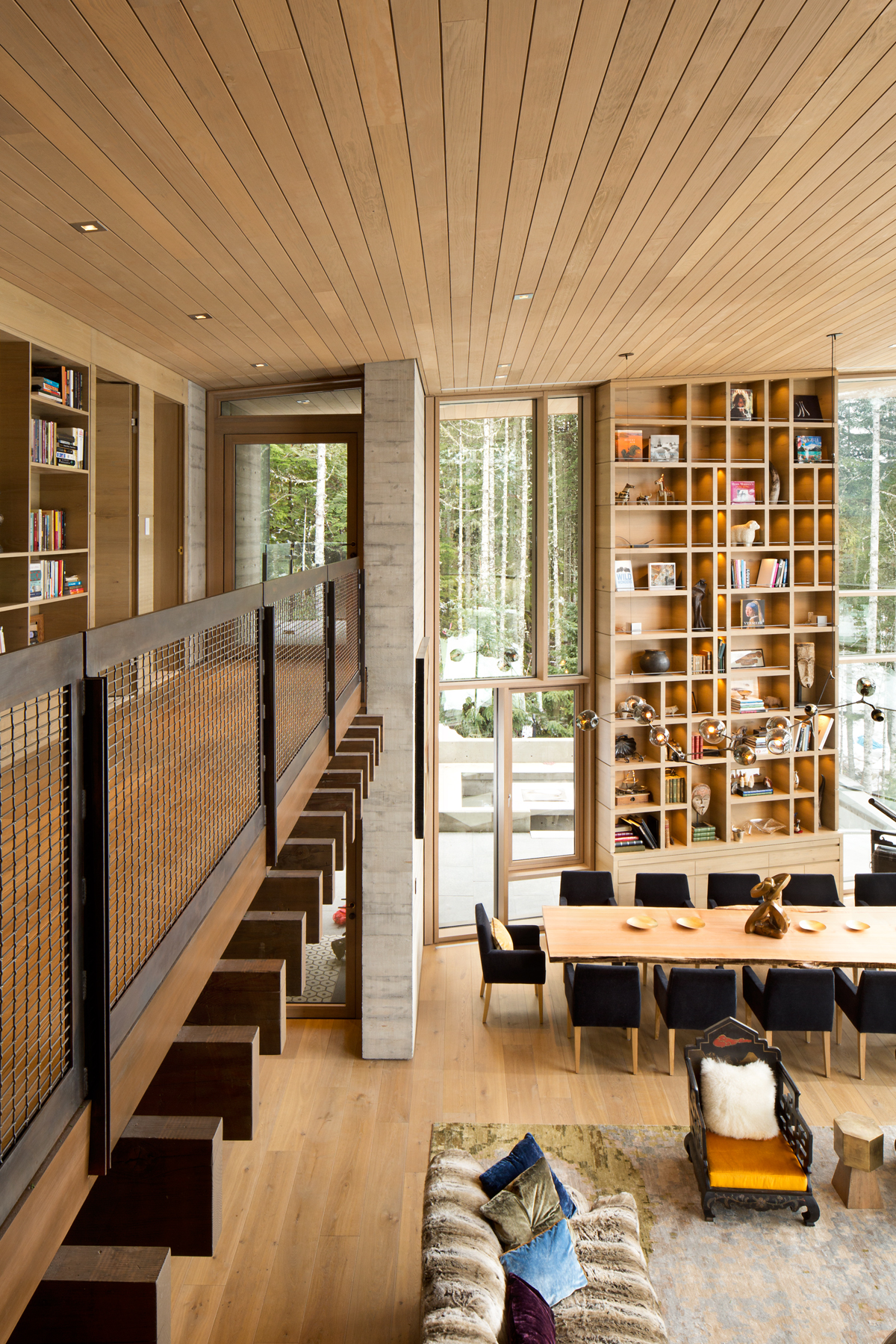 Living space with tall bookshelves, large windows, wooden ceiling, and a dining area with outdoor view—an elegant reflection of Vancouver architecture in British Columbia.