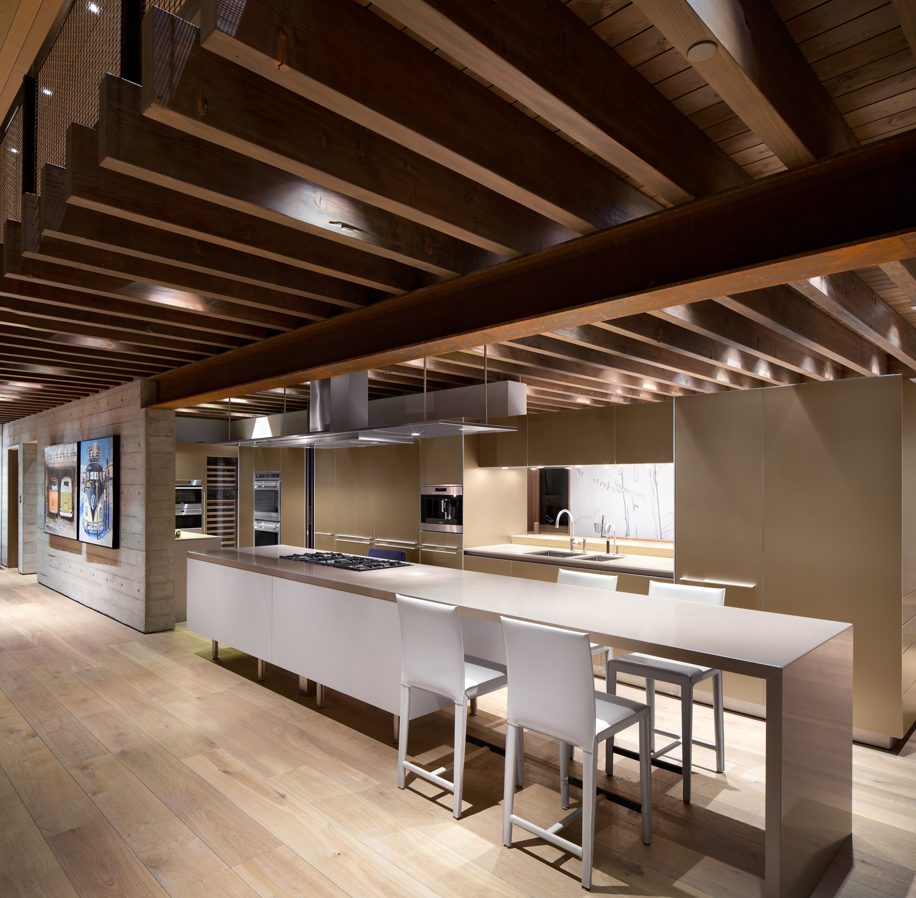 Vancouver kitchen with wood beams, island, white chairs, stainless appliances, and sleek beige cabinets—showcasing quality design found in custom homes.