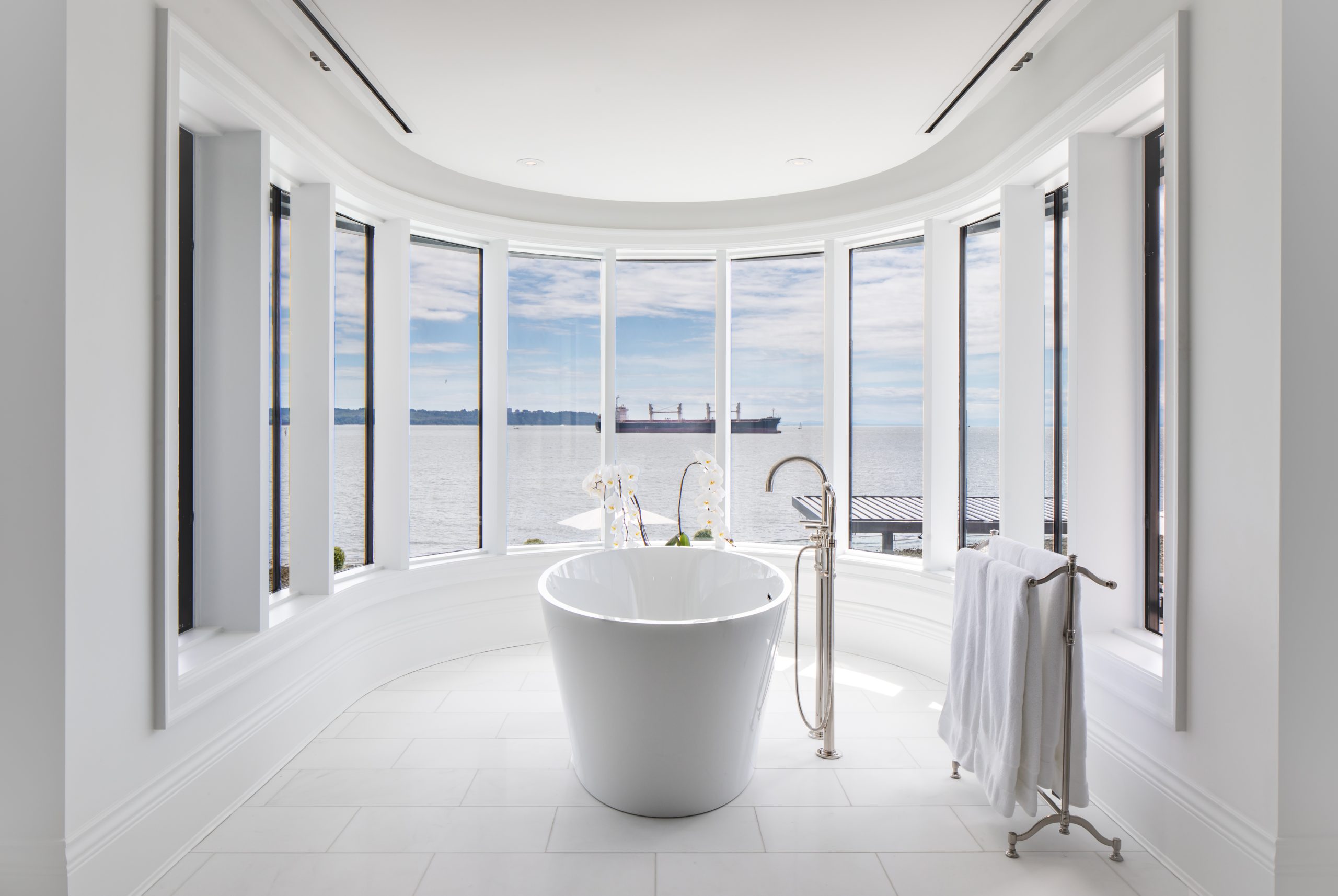 Bathroom with a freestanding bathtub and large bay windows overlooking the ocean, showcasing stunning British Columbia views and elegant custom homes architecture.