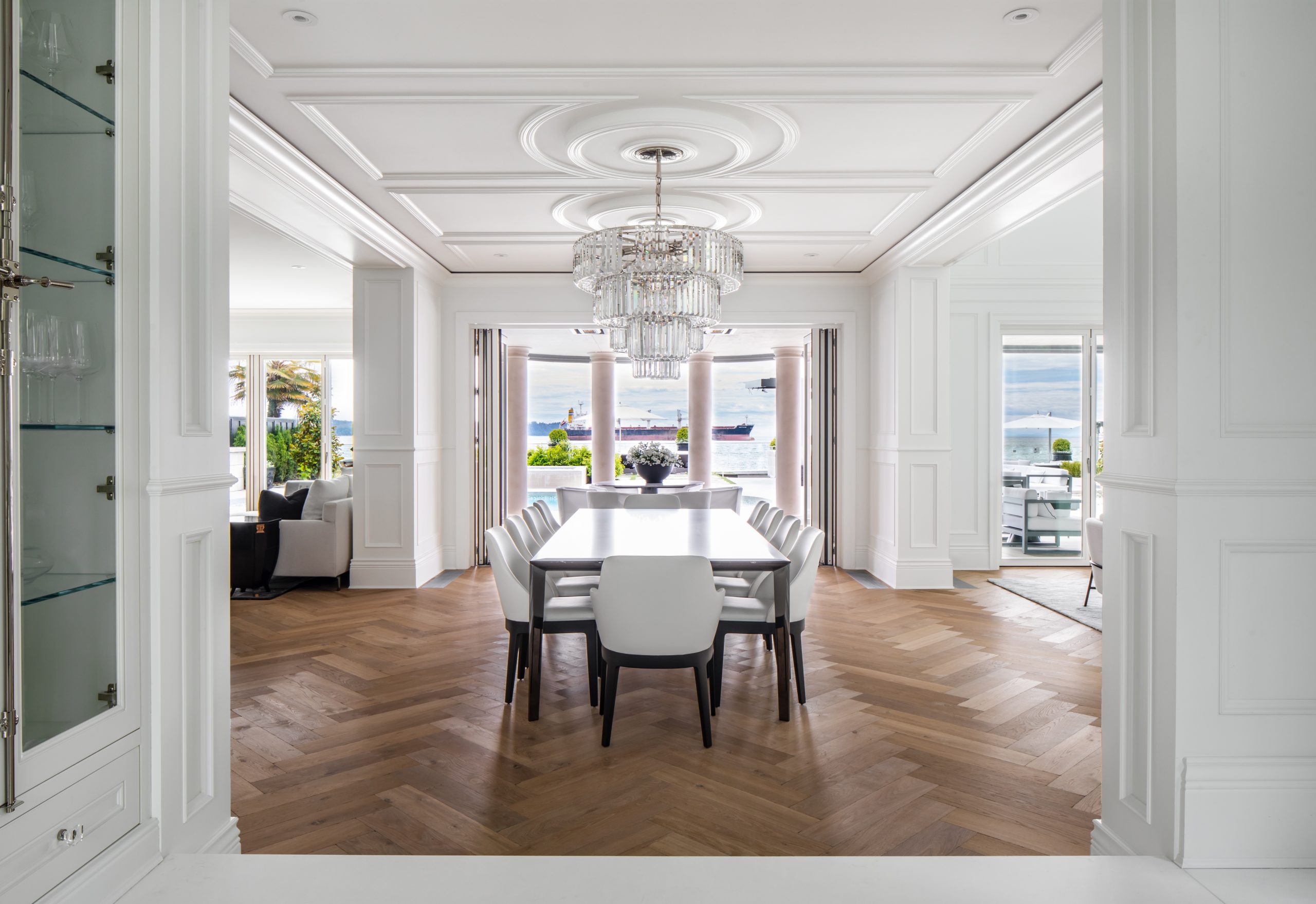 Elegant dining room with white walls, chandelier, large windows, and a table set for ten—perfect for gatherings in quality custom homes crafted by a reputable construction company in Vancouver