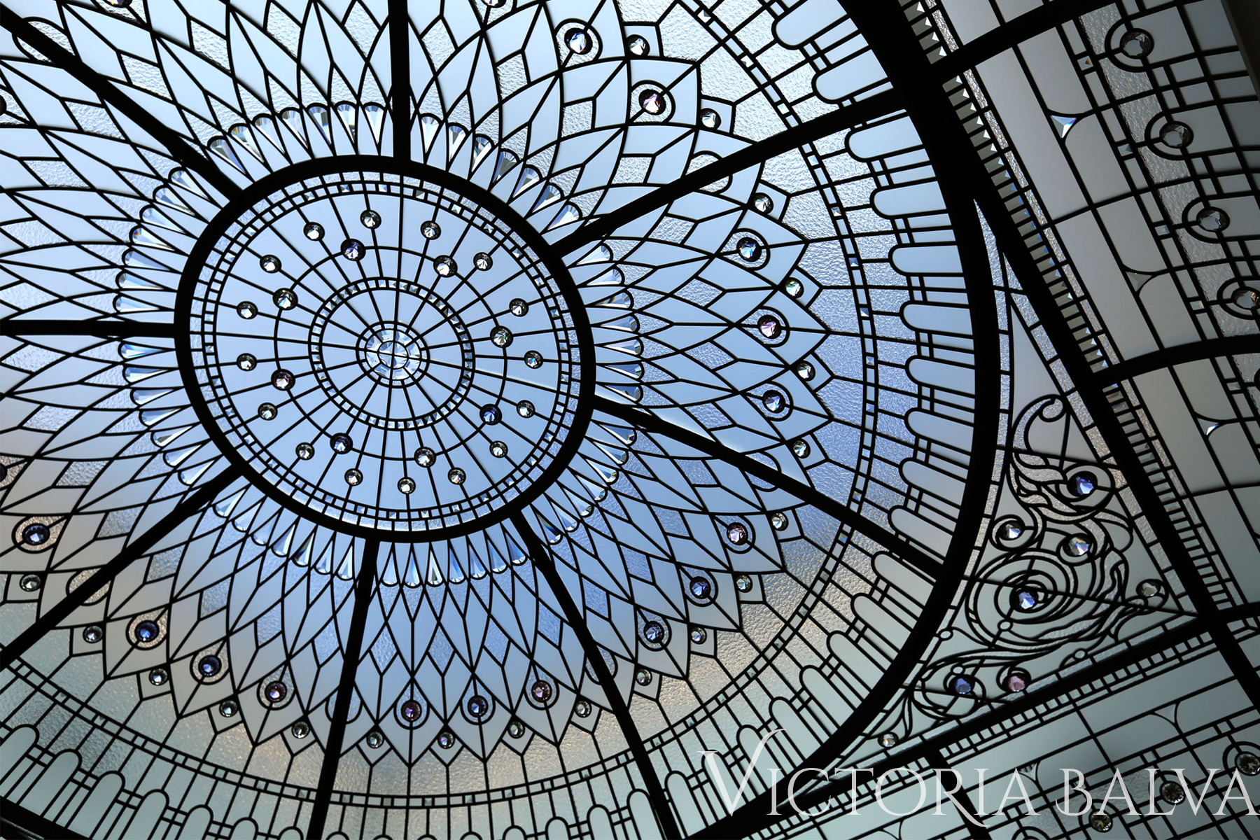 Stained glass dome ceiling with intricate geometric patterns and blue-tinted glass.